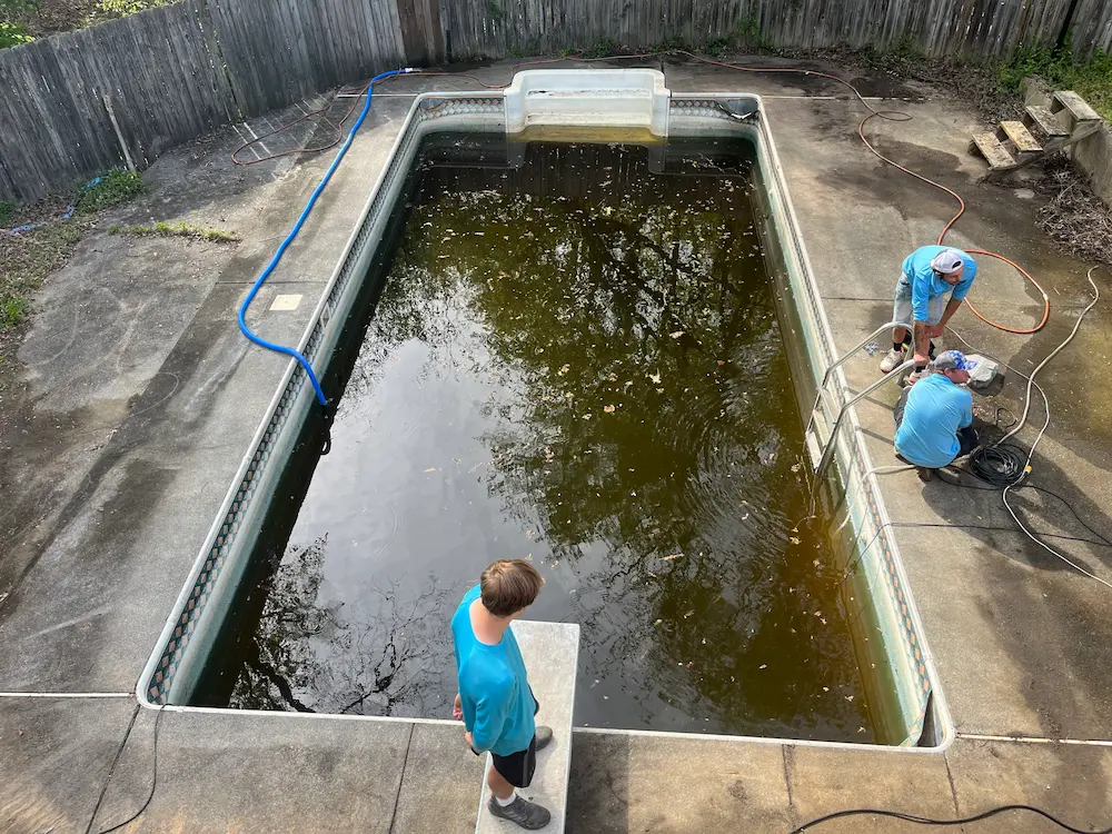 Pool being drained, with technicians at the deep end