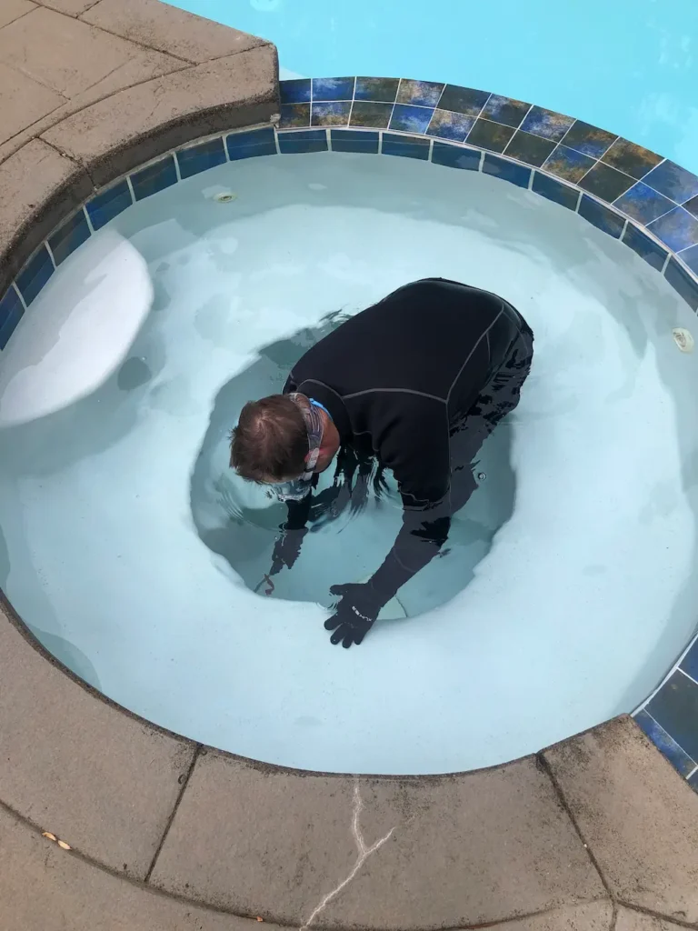 Technician working inside a drained spa with a white finish